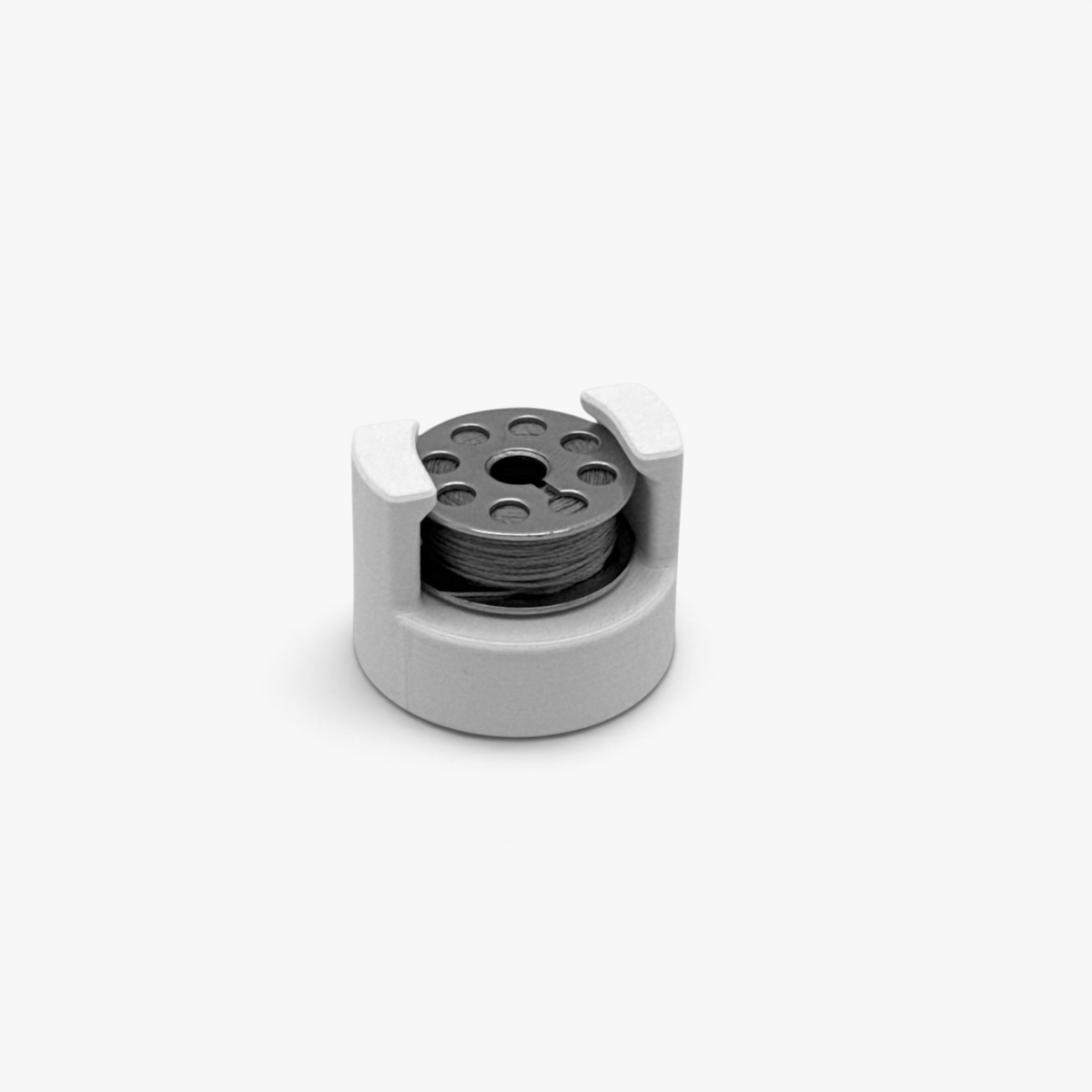 White FŪTL Bobbin Top accessory designed to hold a bobbin on top of industrial sewing thread spool shown with size or style M thread bobbin.