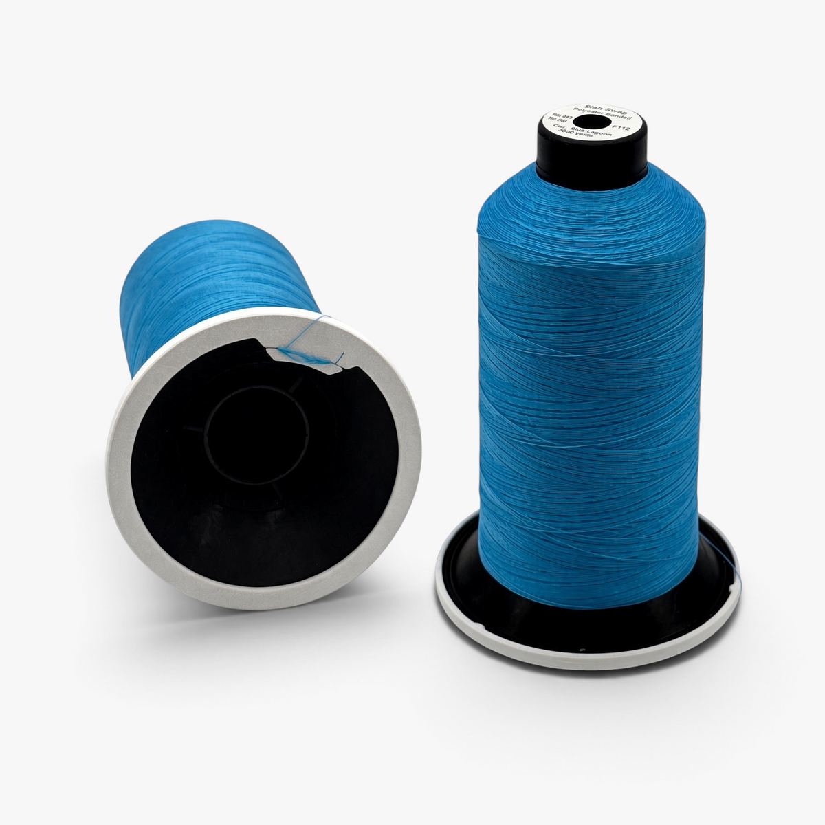 FŪTL Spool Savers attached to blue industrial thread spools, featuring a tangle tab to secure loose thread ends.